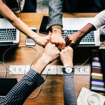 Photo of hands fist bumping over computers