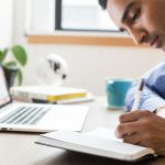 Photo of a man writing in a notebook