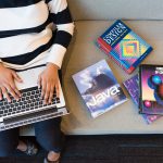 Woman working at a laptop with books