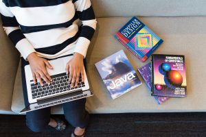 Woman working at a laptop with books