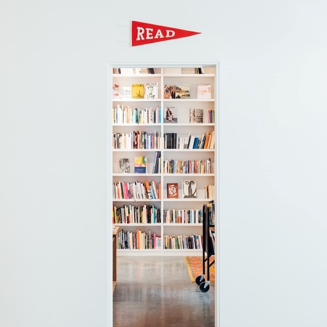 A peak of a private, cozy, library from the view of a thin doorframe with a sign that says, "read."