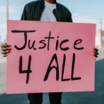 Man holding a sign that says Justice For All