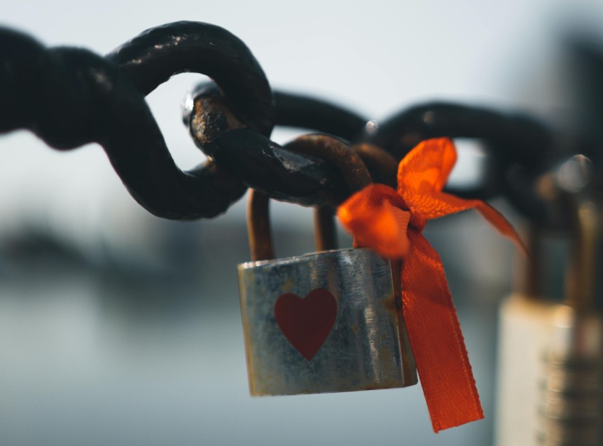 Close-up of a heart-shaped love padlock with a red ribbon on a metal chain in Liverpool